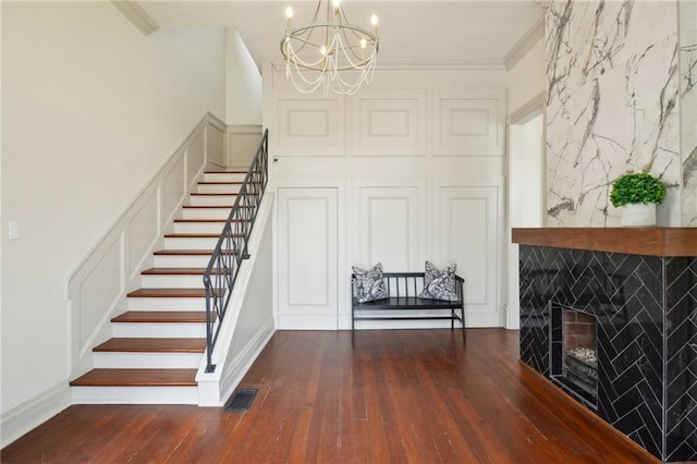 stairs featuring a chandelier, hardwood / wood-style flooring, a fireplace, and ornamental molding