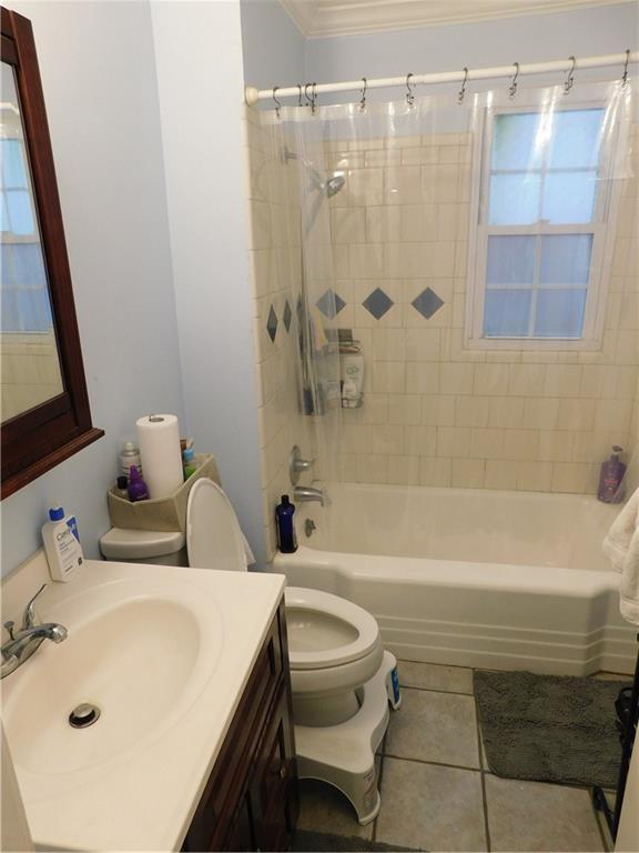 full bathroom featuring tile patterned flooring, tiled shower / bath combo, toilet, and ornamental molding