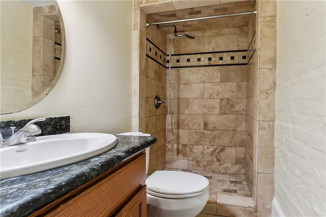 bathroom with toilet, vanity, and tiled shower