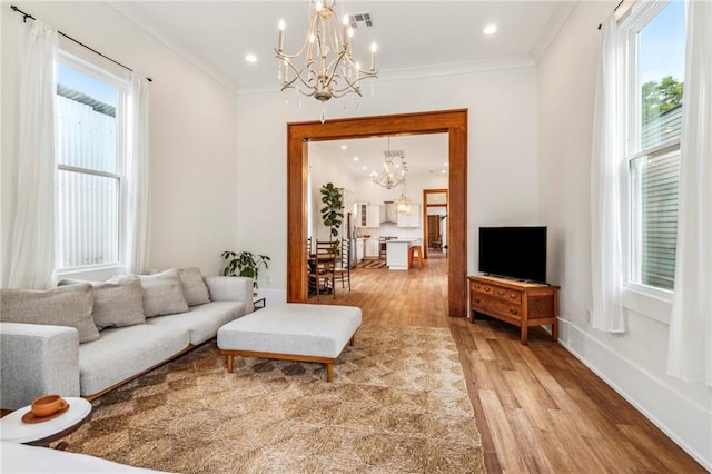 living room featuring hardwood / wood-style floors, a notable chandelier, a healthy amount of sunlight, and crown molding