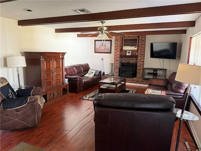 living room with ceiling fan, beamed ceiling, dark hardwood / wood-style floors, and a brick fireplace