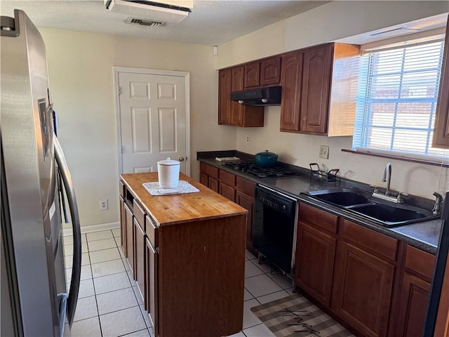 10923 Chaucer St, New Orleans, LA 70127 - kitchen with appliances with stainless steel finishes, wooden counters, under cabinet range hood, a center island, and light tile patterned floors
