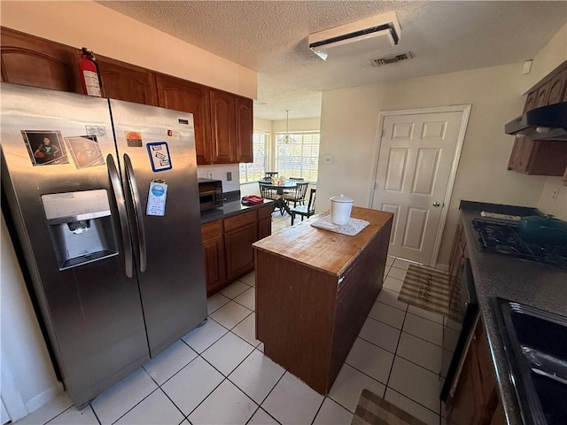 10923 Chaucer St, New Orleans, LA 70127 - kitchen featuring stainless steel fridge, cooktop, under cabinet range hood, a textured ceiling, and wood counters