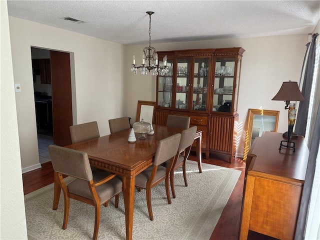 10923 Chaucer St, New Orleans, LA 70127 - dining space with a chandelier, light wood-style flooring, and a textured ceiling