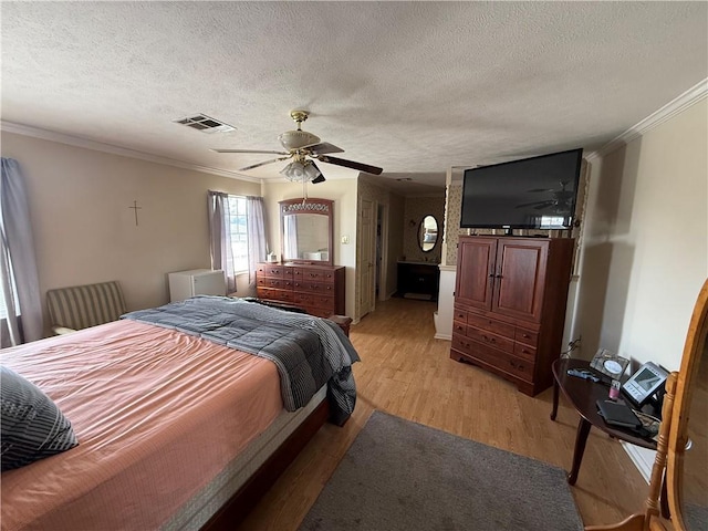 bedroom featuring a textured ceiling, ceiling fan, light wood-type flooring, and ornamental molding