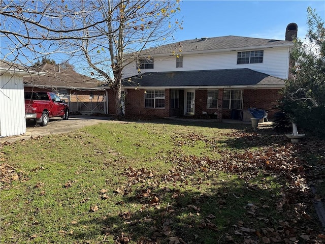 10923 Chaucer St, New Orleans, LA 70127 - back of property with a yard, brick siding, a chimney, a gate, and a carport