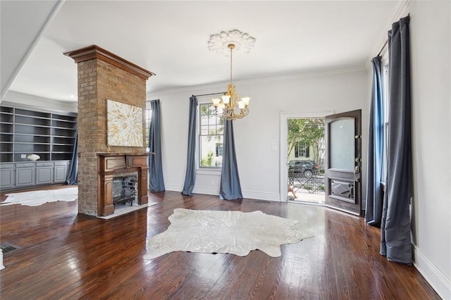 dining area featuring dark hardwood / wood-style flooring, crown molding, a fireplace, and a chandelier