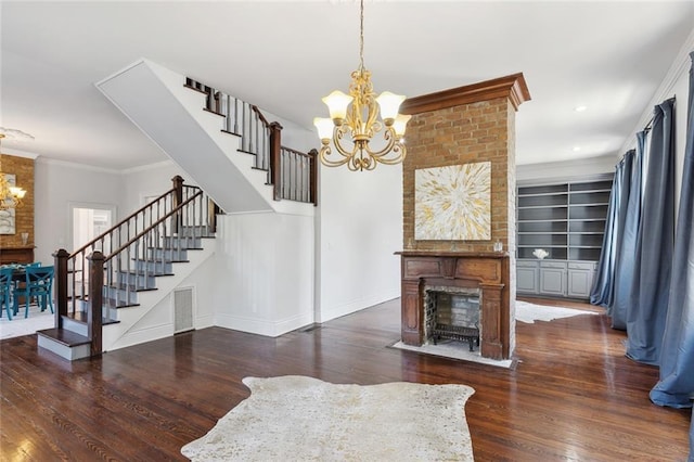 living room featuring crown molding, dark hardwood / wood-style floors, a chandelier, and built in shelves