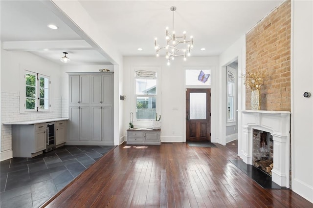 entryway with wine cooler, a chandelier, and dark wood-type flooring