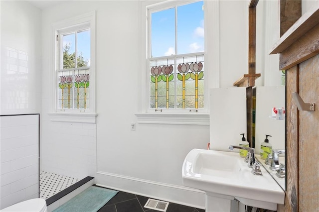 bathroom with tile patterned flooring, sink, toilet, and a tile shower