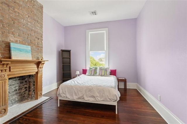 bedroom with dark wood-type flooring and a fireplace