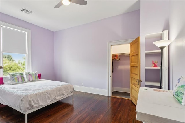 bedroom with dark hardwood / wood-style flooring, a walk in closet, and ceiling fan