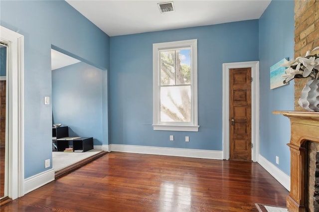 unfurnished bedroom featuring a large fireplace and dark hardwood / wood-style flooring