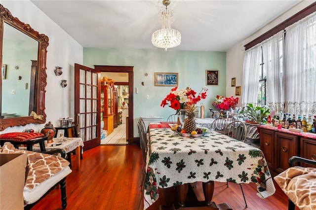 dining area with hardwood / wood-style flooring, a notable chandelier, and french doors