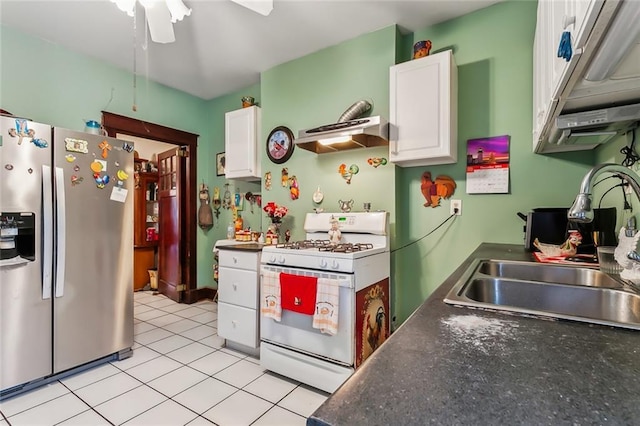 kitchen featuring white gas range, sink, range hood, stainless steel fridge, and white cabinets