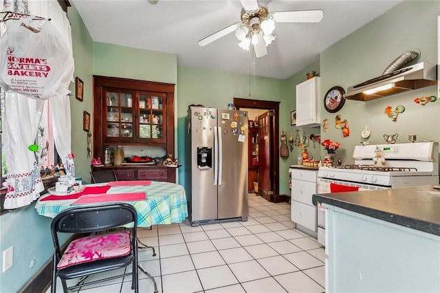 kitchen with ceiling fan, light tile patterned flooring, stainless steel fridge, white cabinets, and white gas range oven