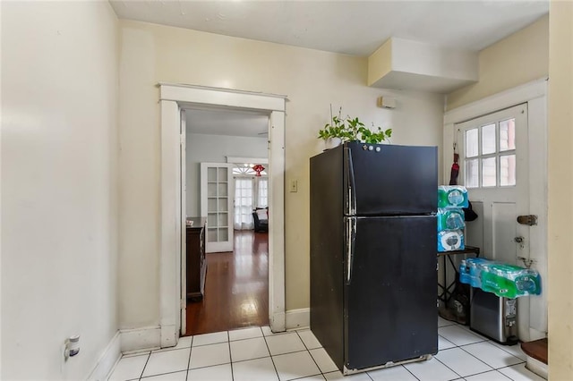 kitchen with french doors, black fridge, a wealth of natural light, and light tile patterned flooring