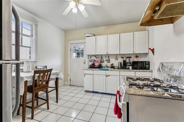 kitchen with white cabinetry, ceiling fan, white range with gas stovetop, extractor fan, and light tile patterned floors