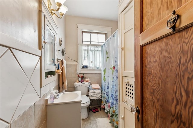 bathroom featuring vanity, toilet, and tile walls