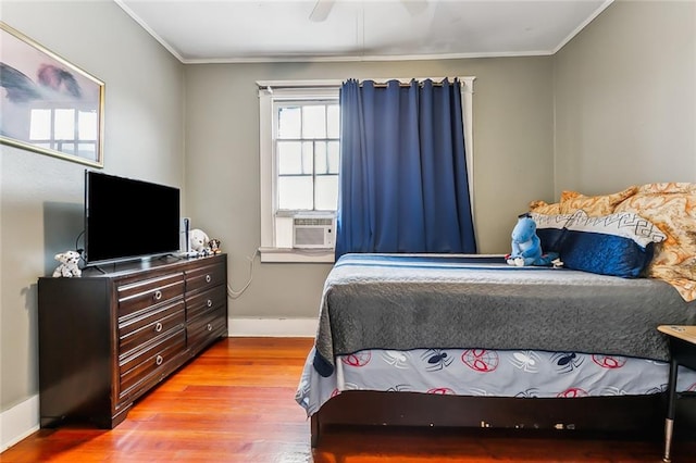 bedroom with ceiling fan, cooling unit, ornamental molding, and light hardwood / wood-style flooring