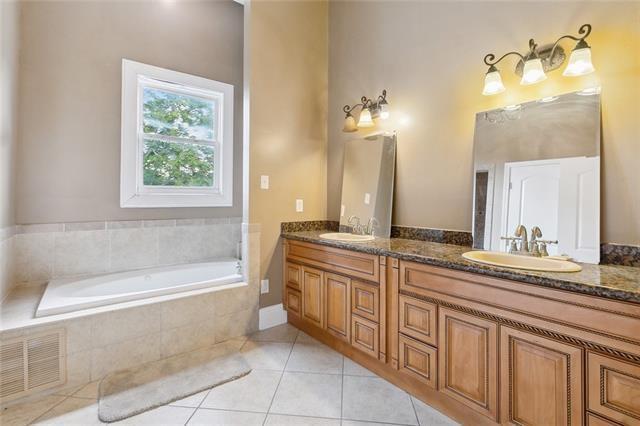 bathroom featuring tiled tub, tile patterned flooring, and vanity