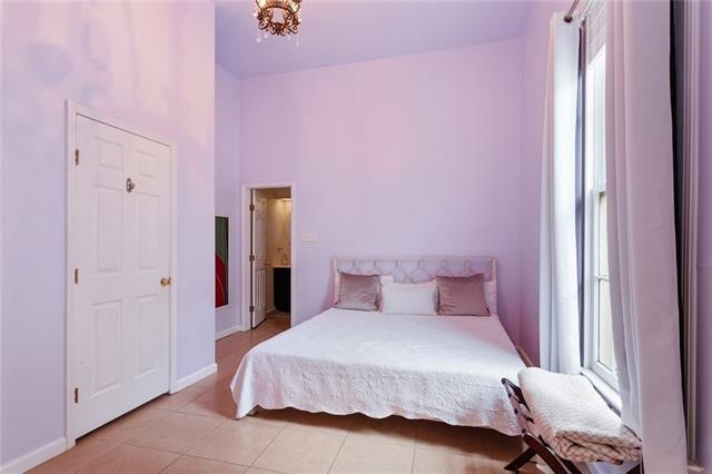 tiled bedroom featuring a chandelier and multiple windows