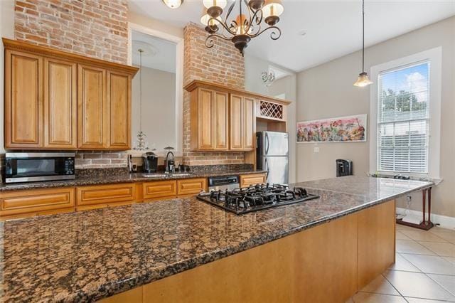 1027 Ninth St, New Orleans, LA 70115 - kitchen featuring stainless steel appliances, backsplash, dark stone countertops, a chandelier, and light tile patterned floors
