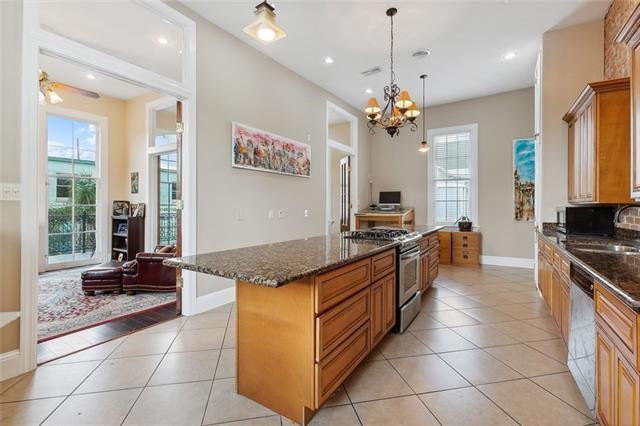 1027 Ninth St, New Orleans, LA 70115 - kitchen with appliances with stainless steel finishes, dark stone counters, a chandelier, light tile patterned floors, and a kitchen island