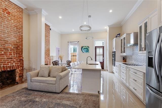 1027 Ninth St, New Orleans, LA 70115 - kitchen with stainless steel appliances, wall chimney range hood, light countertops, a center island with sink, and ornamental molding