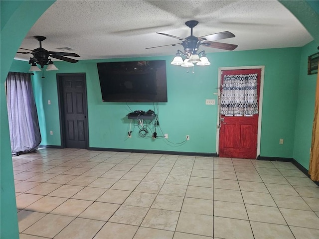 unfurnished living room featuring ceiling fan, light tile patterned flooring, and a textured ceiling