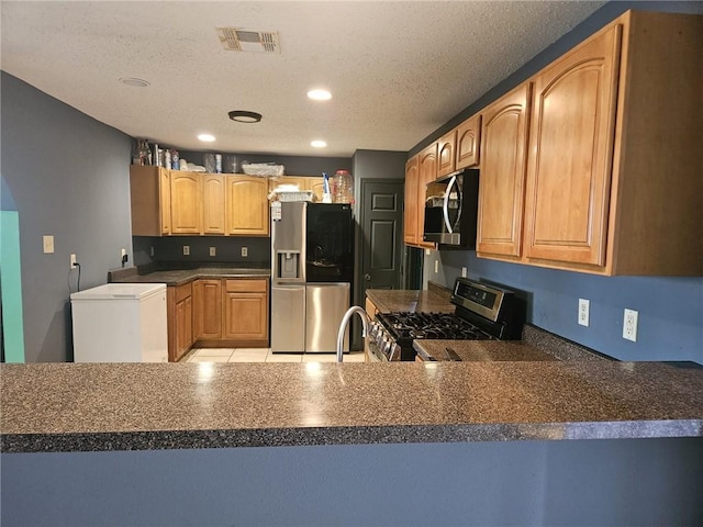 kitchen with a textured ceiling, kitchen peninsula, and stainless steel appliances