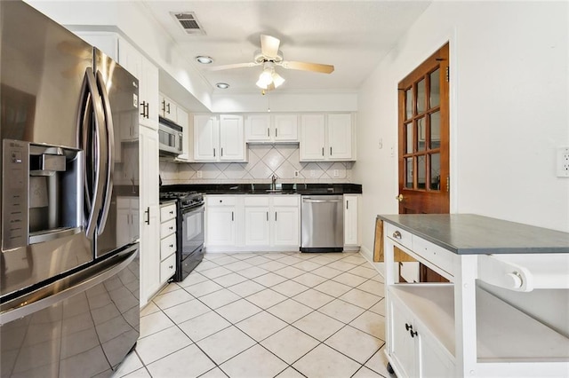 kitchen featuring light tile patterned floors, white cabinetry, appliances with stainless steel finishes, backsplash, and sink