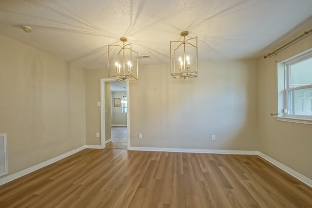 unfurnished room featuring hardwood / wood-style flooring and a notable chandelier