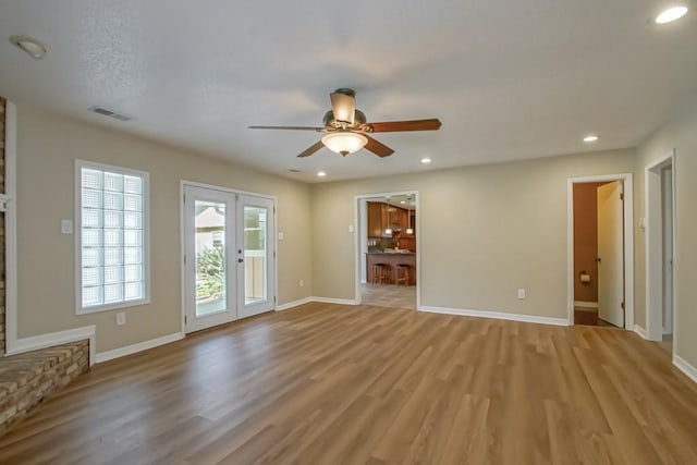 interior space featuring a stone fireplace, ceiling fan, french doors, and light hardwood / wood-style flooring