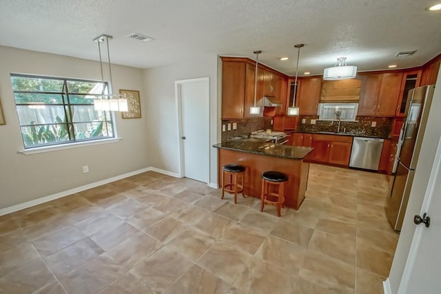 kitchen with a breakfast bar, dark stone countertops, appliances with stainless steel finishes, decorative light fixtures, and kitchen peninsula