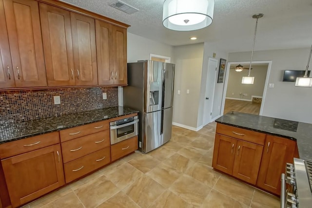 kitchen featuring dark stone countertops, decorative backsplash, hanging light fixtures, and appliances with stainless steel finishes