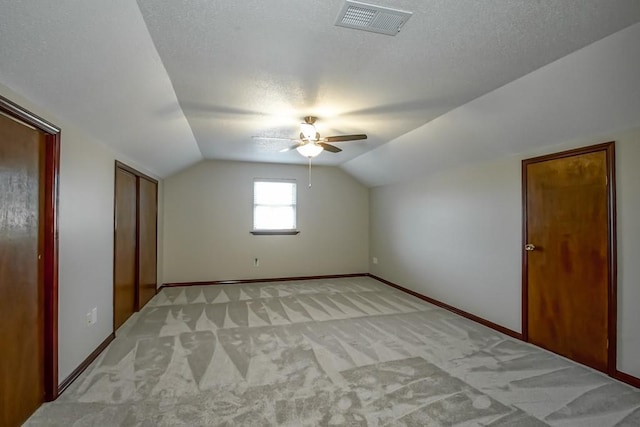 bonus room featuring ceiling fan, light colored carpet, a textured ceiling, and vaulted ceiling