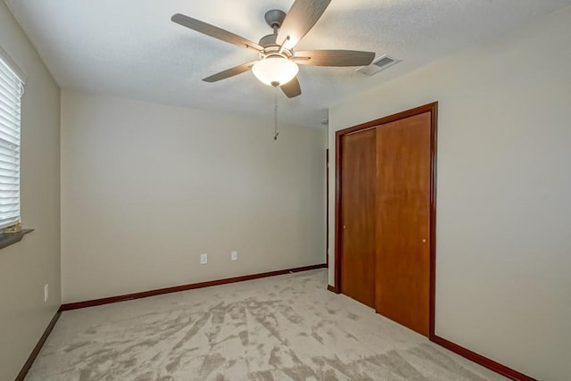 unfurnished bedroom with ceiling fan, light colored carpet, and a closet