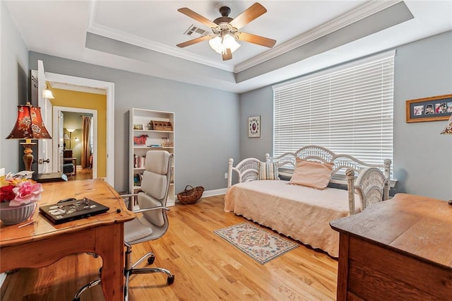 bedroom with ornamental molding, a tray ceiling, baseboards, and wood finished floors