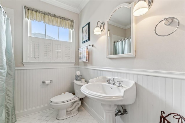 full bath with crown molding, a shower with curtain, toilet, wainscoting, and tile patterned flooring