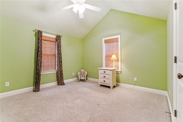 interior space featuring carpet floors, vaulted ceiling, baseboards, and a ceiling fan