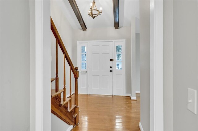 entrance foyer featuring beamed ceiling, an inviting chandelier, and light hardwood / wood-style flooring