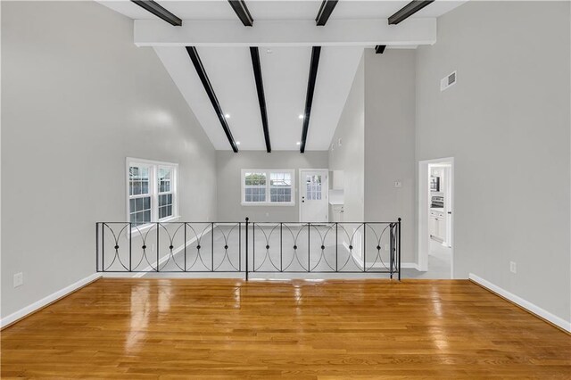 stairs featuring a healthy amount of sunlight, beam ceiling, and high vaulted ceiling