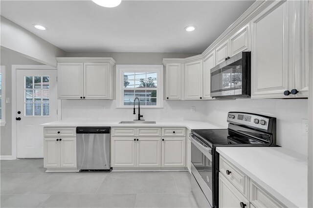 kitchen with light tile patterned floors, stainless steel fridge, and white cabinets