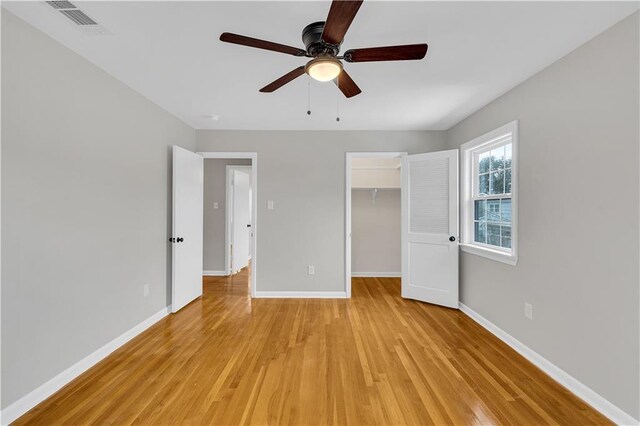 unfurnished bedroom featuring ceiling fan, ensuite bathroom, and light wood-type flooring