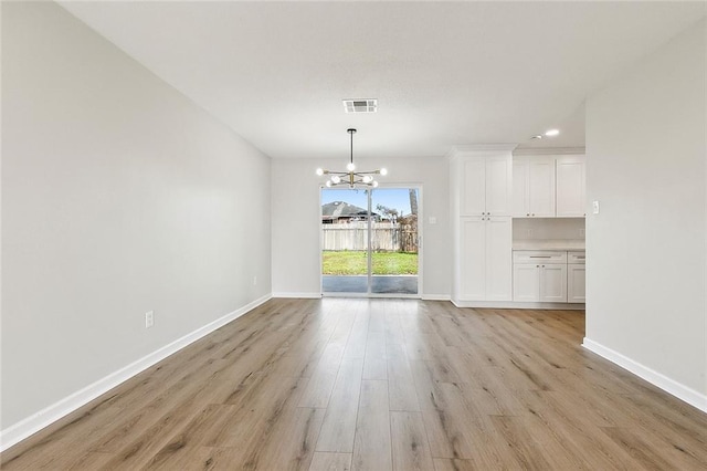 unfurnished dining area with a notable chandelier and light wood-type flooring