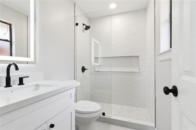 bathroom with tiled shower, vanity, and toilet