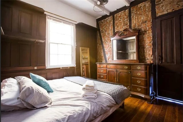 bedroom featuring ceiling fan, brick wall, and dark hardwood / wood-style floors