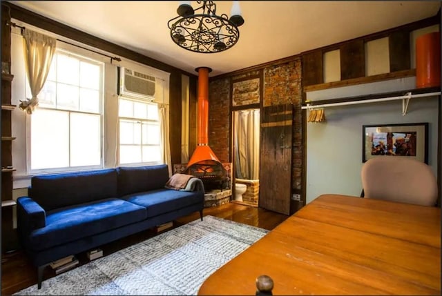 living room featuring a wall unit AC, a wood stove, and wood-type flooring