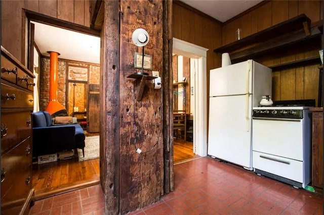 kitchen featuring wooden walls, stove, ornamental molding, and white refrigerator